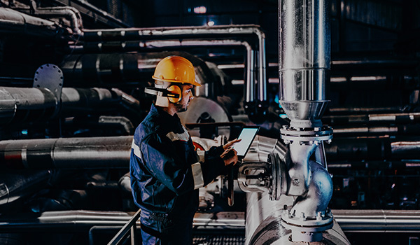 A Heat Networks engineer gathers energy data on a tablet device in a heating plant.