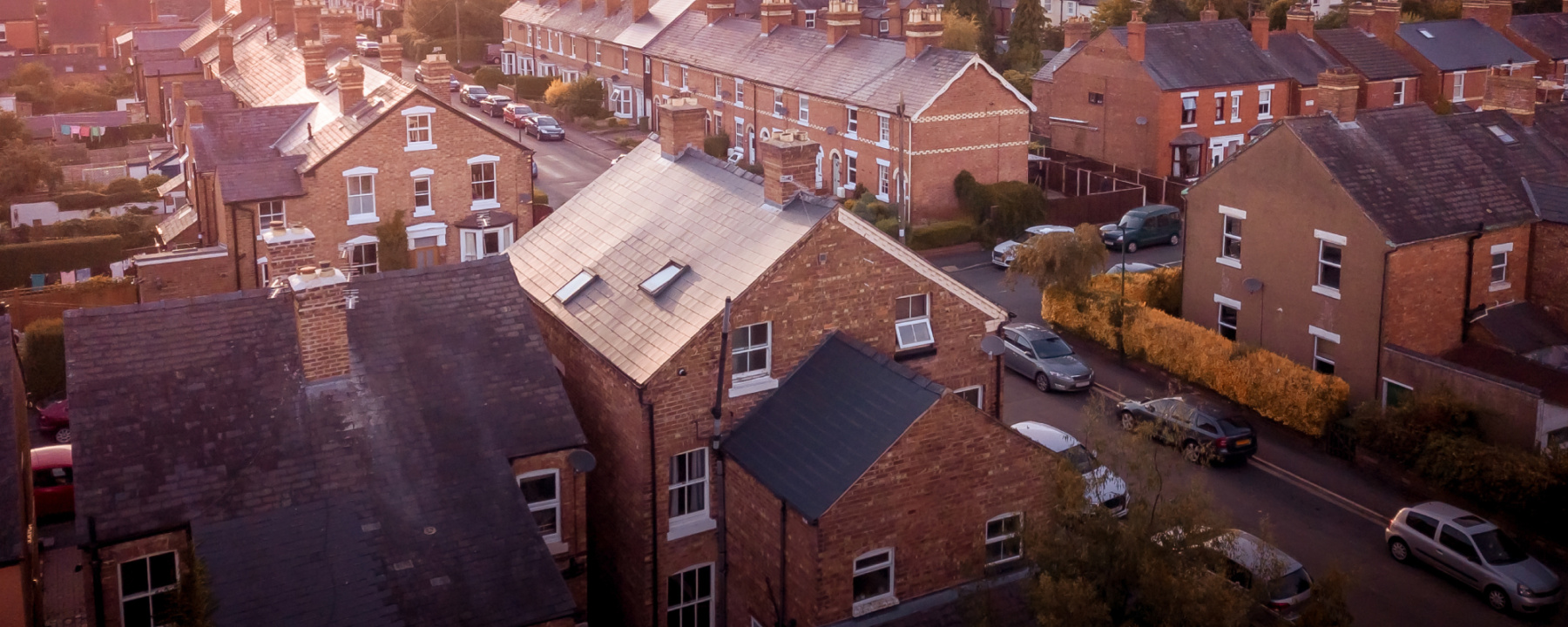 Sun setting with atmospheric effect over traditional British houses and tree lined streets
